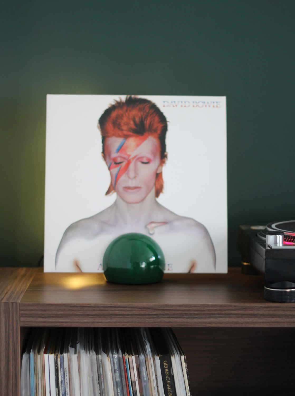 Vinyl record with a cover featuring David Bowie placed on a shelf with records.